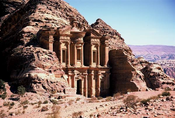 Petra's Monastery carved into red rock under a blue sky