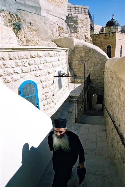 Orthodox monk with white beard descends stone stairs at Mar Saba monastery