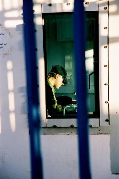 Soldier in cap behind the window of a white booth, filtered light