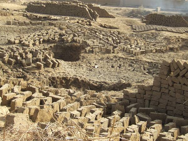 Mud bricks drying in the sun at a sandy brickyard