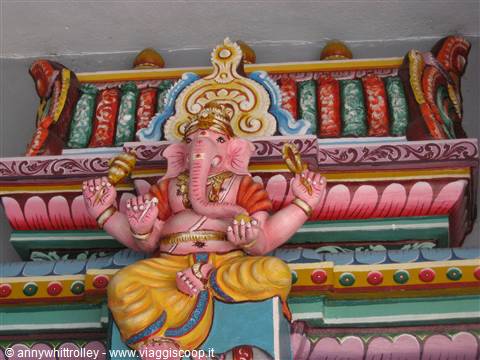Painted four-armed Ganesha statue on colorful Hindu temple gopuram