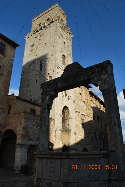 Medieval stone tower rising above an old well in San Gimignano, sunlight