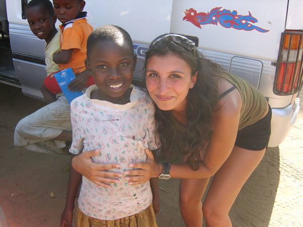 Tourist hugs a smiling child beside a white van