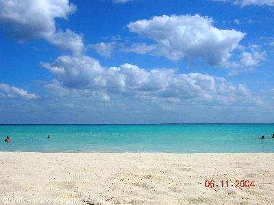 White sand beach, turquoise sea with swimmers, blue sky with clouds