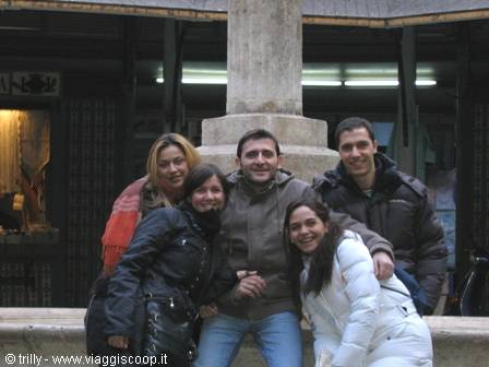 Five friends smiling in front of a stone fountain in a square