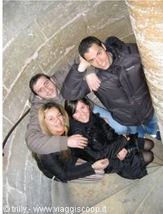 Four friends hugging on a stone spiral staircase inside a tower
