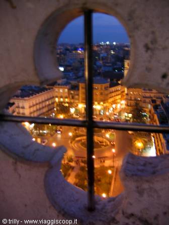 Lit square seen through a stone quatrefoil window at dusk