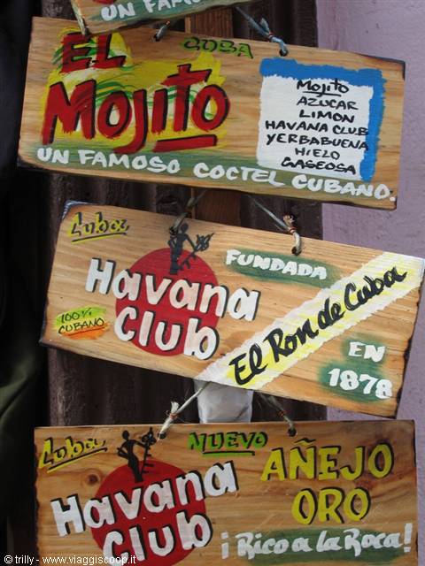 Hand-painted wooden signs for Havana Club rum and Cuban mojito hanging on a post
