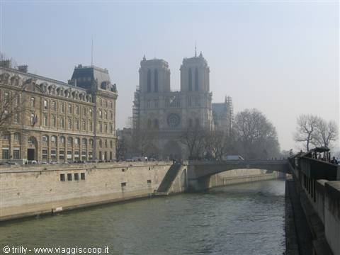 Notre-Dame Cathedral in fog, with the Seine river and a bridge in front
