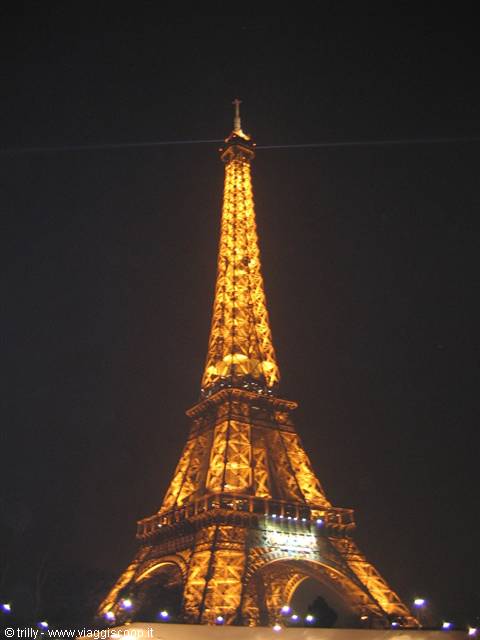 The Eiffel Tower's iron lattice glowing golden at night in Paris