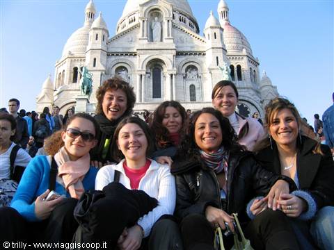 Group of smiling friends in front of the Sacré-Cœur basilica in Paris