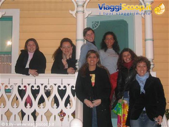 Group of smiling young women on yellow wooden porch with white railing