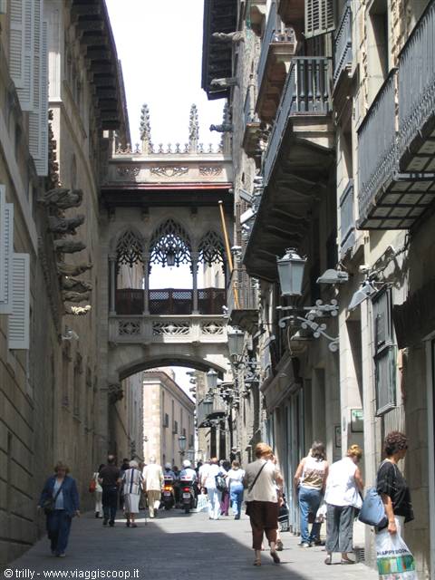 Tourists walk beneath the Gothic bridge on Carrer del Bisbe in Barcelona