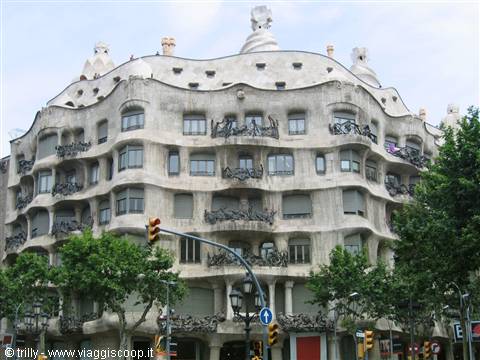 Gaudí's La Pedrera in Barcelona, wavy stone facade among green trees