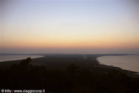 Orange sky above two sea stretches separated by a dark coastal strip