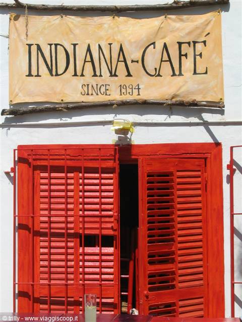 Hand-painted Indiana-Café sign above open red shutters in sunlight
