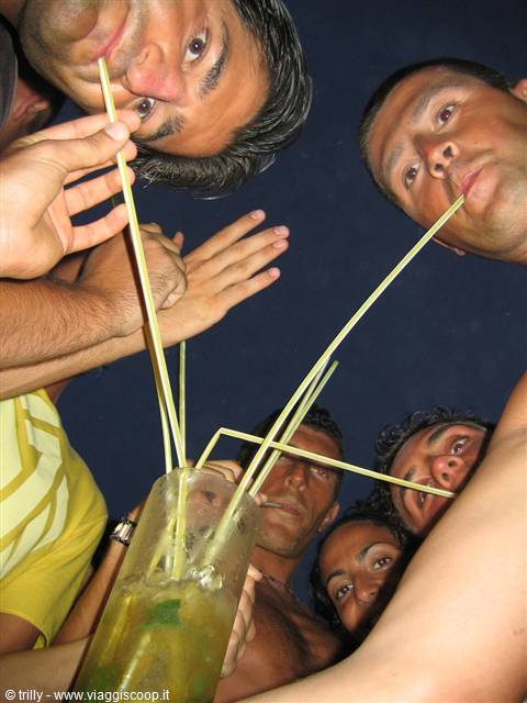 Group of friends drinking mojito with long straws from one glass