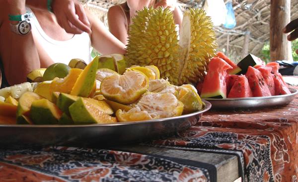 Metal trays with durian, watermelon and mango on a batik-covered table