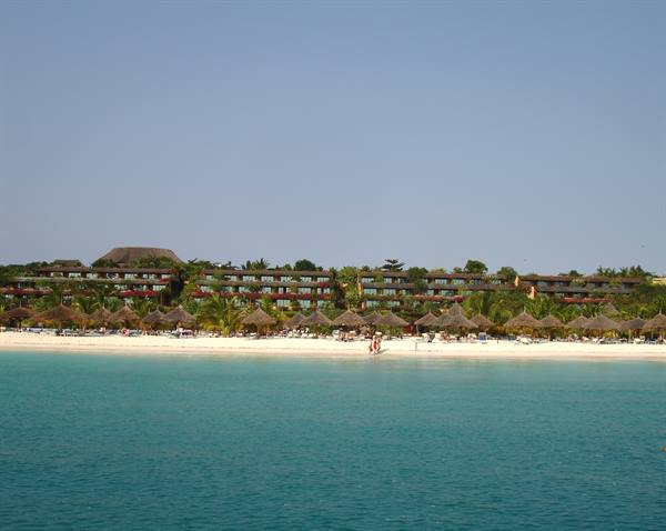 White sand beach with straw umbrellas, palm-lined resort and turquoise sea