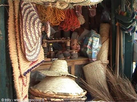 Straw hats hanging in a craft stall with colorful ropes and brooms