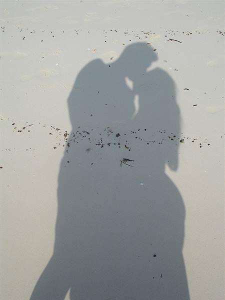 The shadow of a kissing couple cast on pale sand