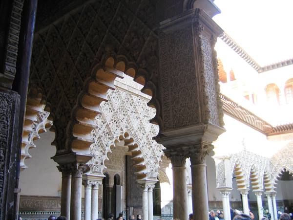 Carved polylobed arches and marble columns in Seville's Alcázar courtyard