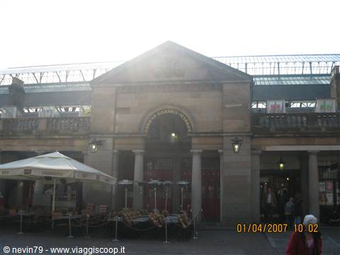 Covent Garden in London: stone facade with golden medallion, white umbrellas and fruit stalls