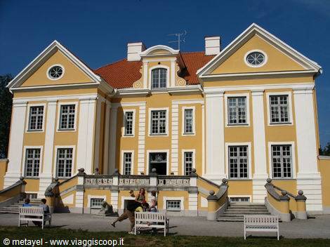 Tourists sitting on benches in front of Palmse yellow manor house