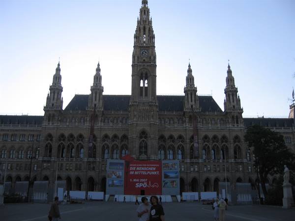 Vienna City Hall, neo-Gothic stone facade with central tower, people strolling at dusk