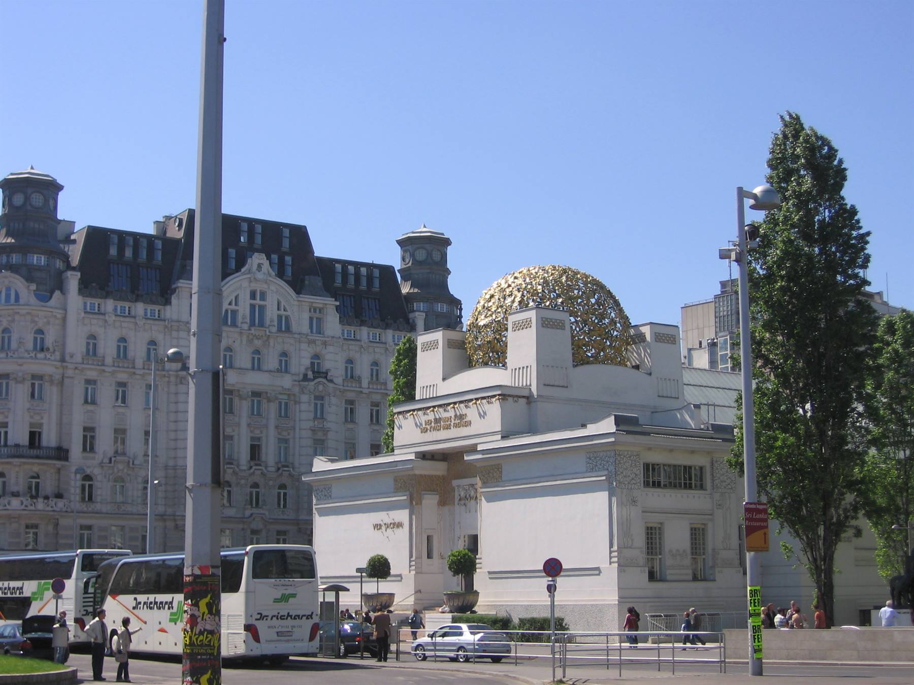 Vienna Secession building, golden dome of aluminum leaves, buses and pedestrians under sun