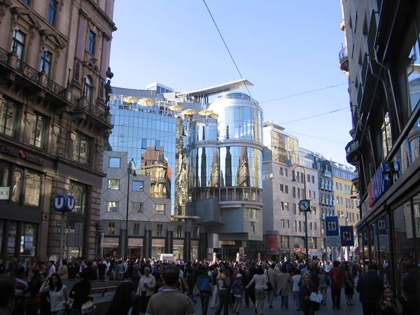Crowd on Vienna pedestrian street, Haas House glass facade reflects the cathedral