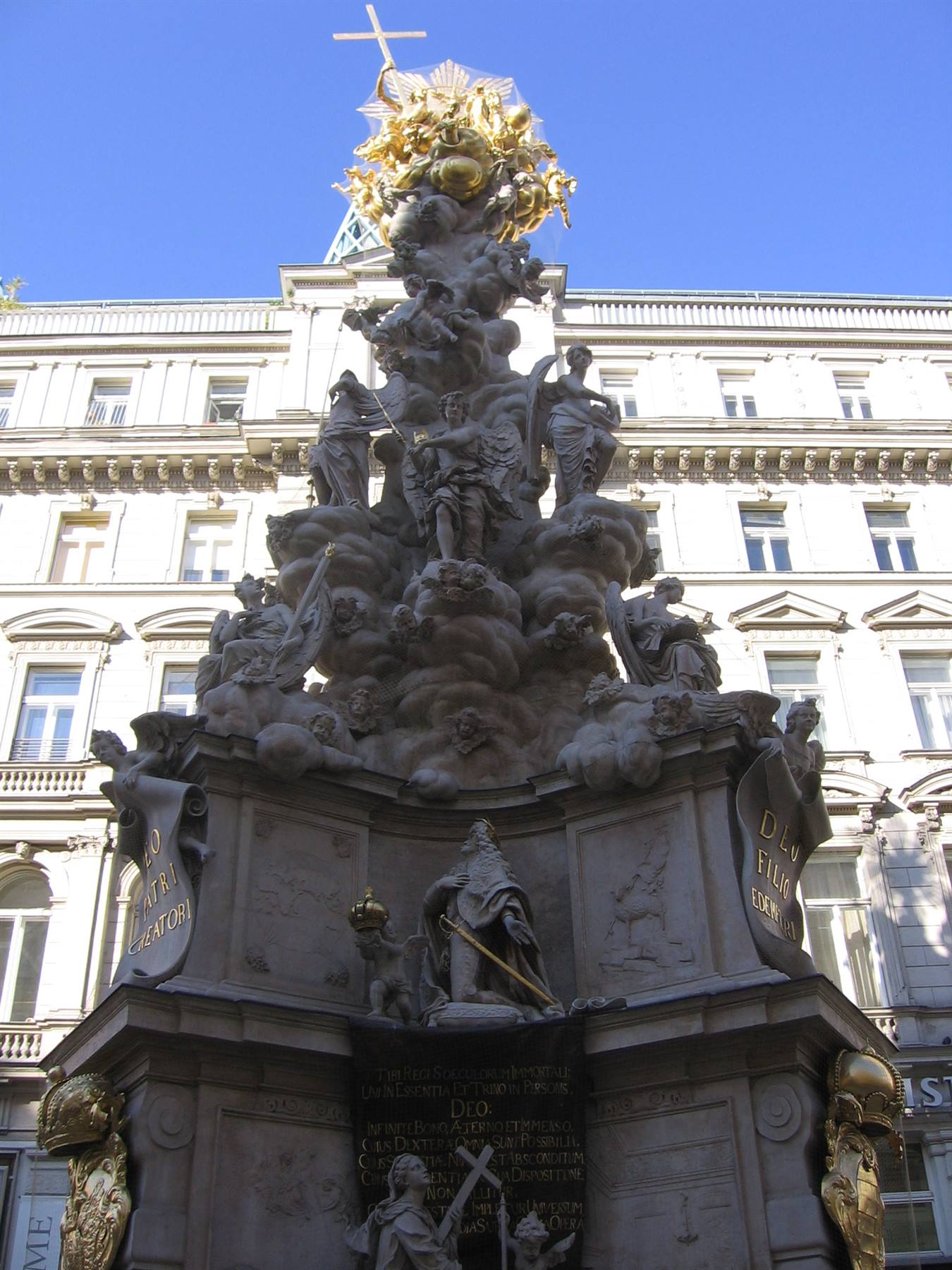 Baroque marble column with golden sculptures against a white building, Vienna