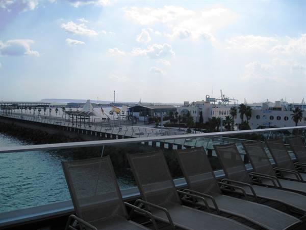 Deck chairs on cruise ship deck facing the port, cloudy sky