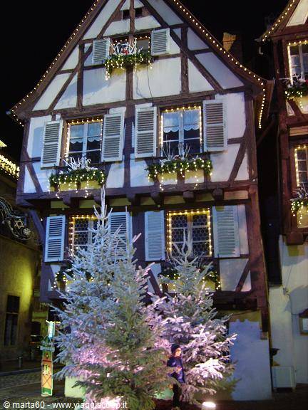 Half-timbered house decorated with Christmas lights and lit fir trees, Colmar