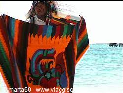 Woman displays a woven blanket with colorful condor design by the sea