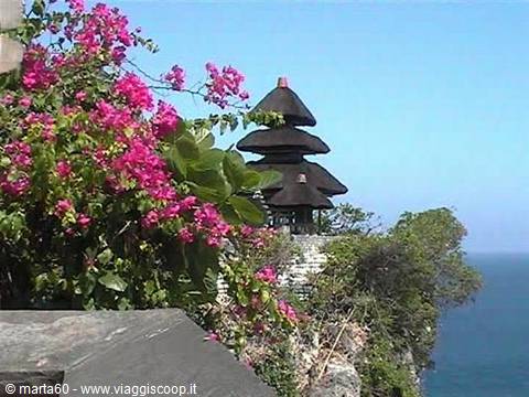 Uluwatu temple on the cliff, black stone pagoda among bougainvillea and ocean