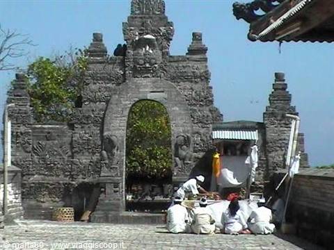 Worshippers in white pray before the stone gate of Uluwatu temple