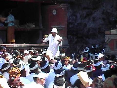 Balinese priest in white leads ceremony among worshippers wearing headbands