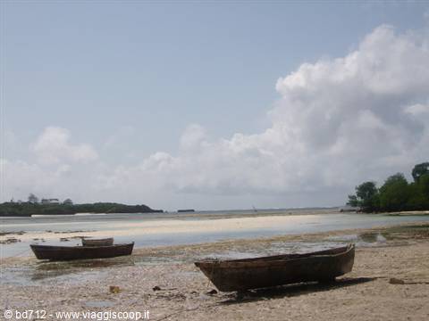 Wooden boats stranded on sandy beach under white clouds