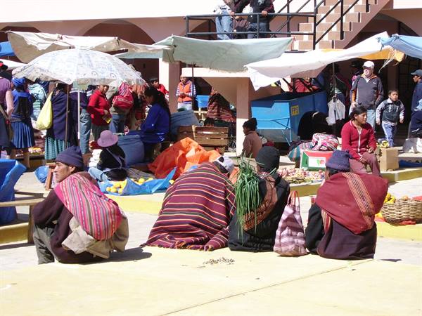 Women in colorful shawls sell green onions at outdoor market