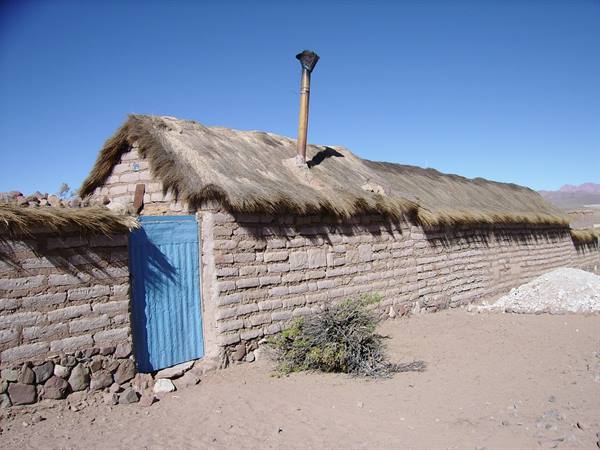 Mud brick house with thatched roof and blue door in the desert