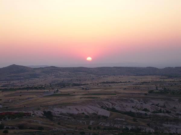 Red sun rising over the arid hills of Cappadocia