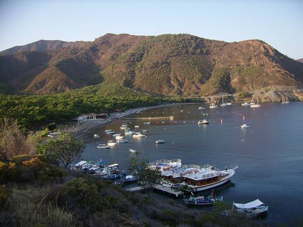 Turkish boats moored in calm bay surrounded by green mountains, golden morning light