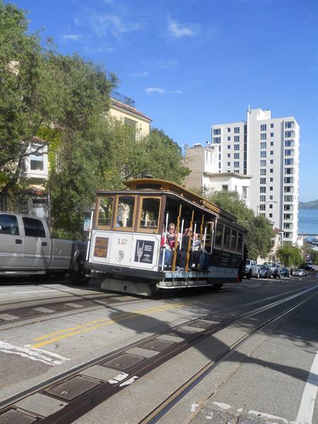 Cable car with passengers climbing steep San Francisco street