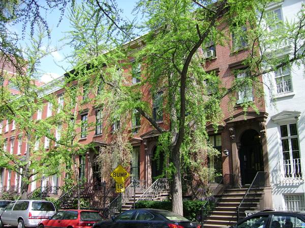 New York red brick brownstones with stone stoops and green leafy trees