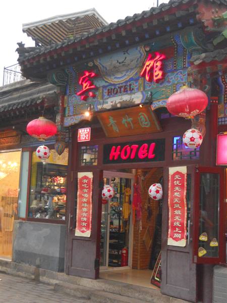 Entrance of a small traditional hotel with red signs, lanterns and decorated roof