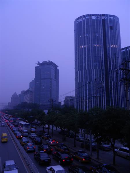Traffic jam beneath glass towers in blue morning haze