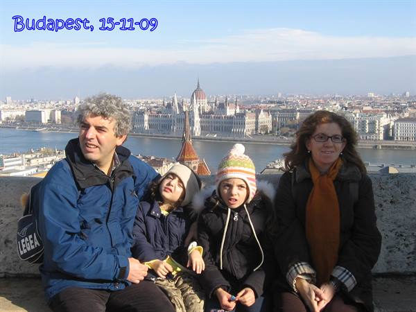 Family of four seated on a terrace in Budapest, Danube and Parliament behind