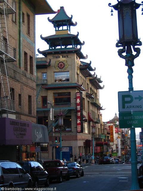 Green pagoda building with Chinese signs above California Street, parked cars