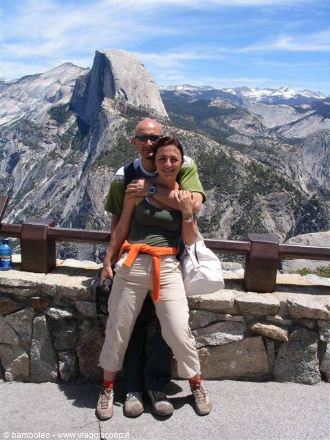 Couple hugging at Glacier Point, Half Dome rising behind in Yosemite